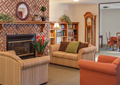 Warmly decorated Creekside gathering area with fireplace, couches, books and a grandfather clock